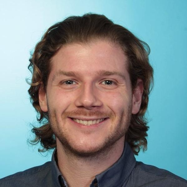 Profilbild des Therapeuten Florian Klopprogge Lächelnder Mann mit lockigem, blondem Haar vor blauem Hintergrund.
